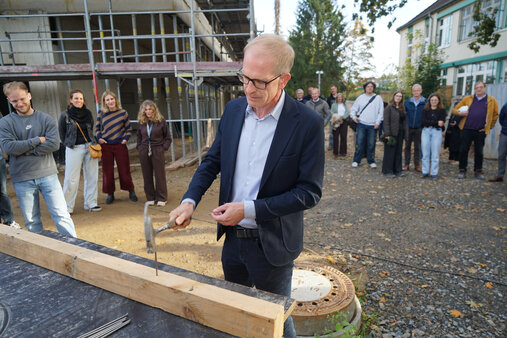 Richtfest Erweiterungsbau Fahlerweg Bürgermeister Gerold Wenzens schlägt die Nägel in die finale Planke des Daches ein.